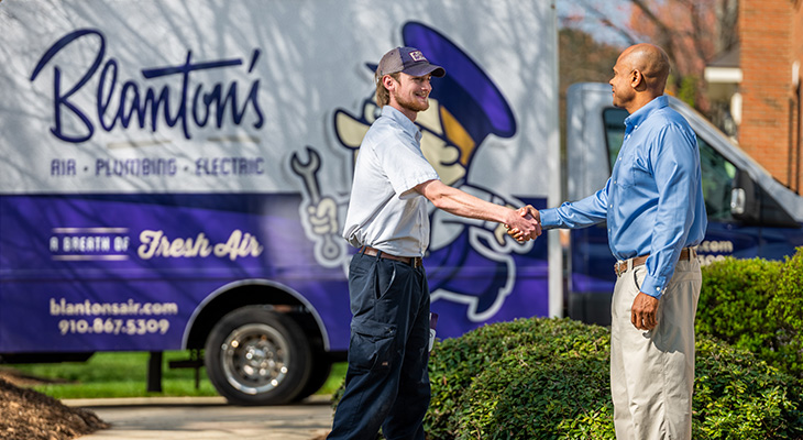 Blanton's service professional shaking the hand of a homeowner in front of work truck