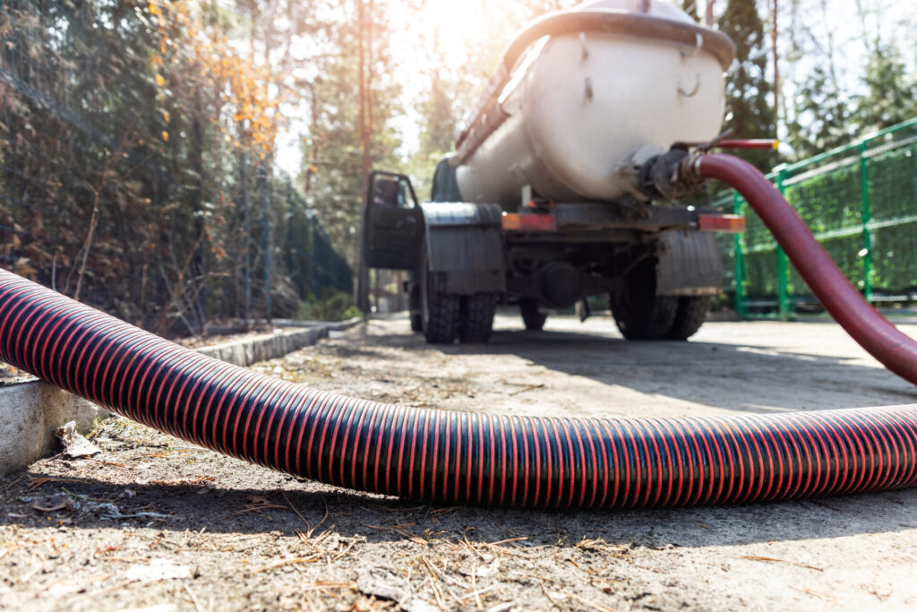 Close-up pipe hose of sewage truck car engine emptying home sewerage tank