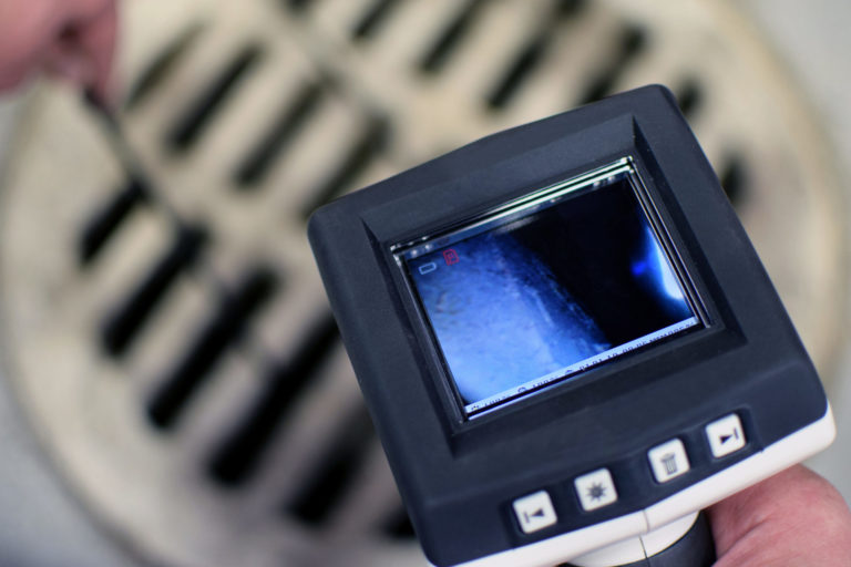 Checking sewer manhole with inspection camera.