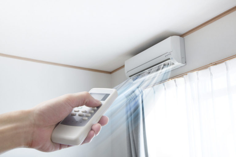 Ductless mini-split installed on wall, being controlled by a remote