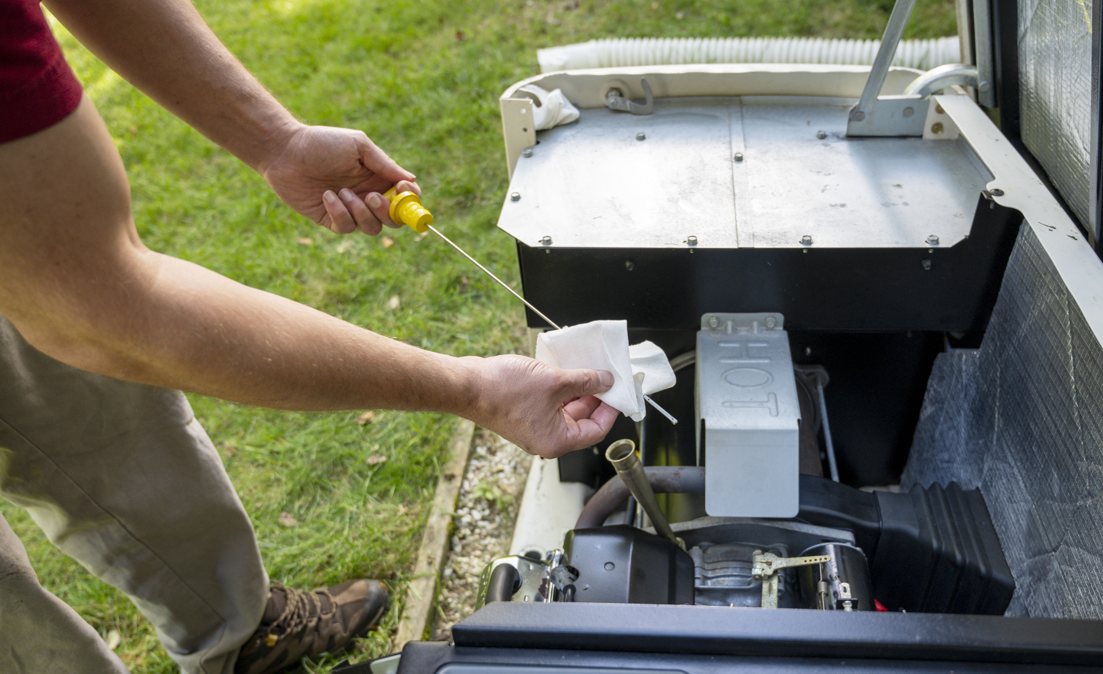 Man checking engine oil in generator, cleaning oil dipstick after measuring oil level