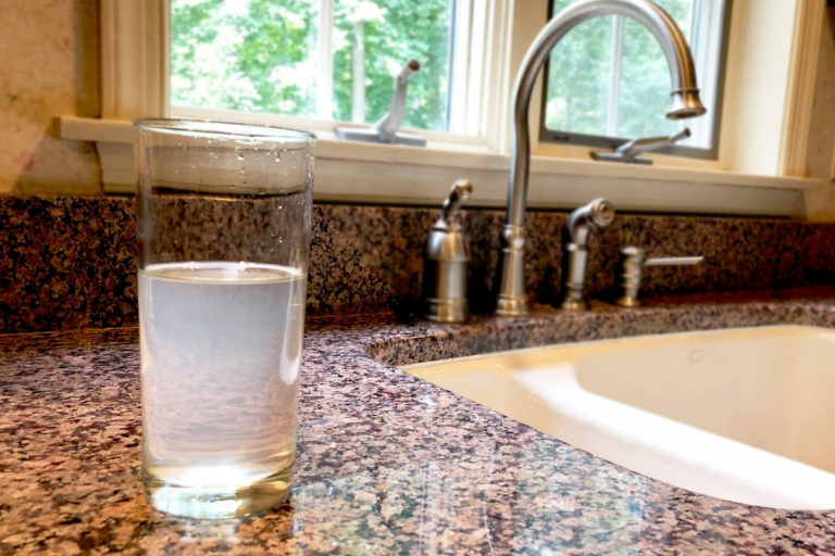 cloudy water in a glass next to a kitchen sink