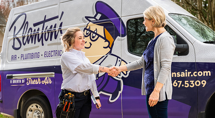 Blanton's service professional shaking the hand of a homeowner in front of work truck