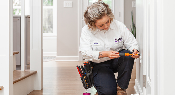 An employee crouches to fix an electrical outlet.