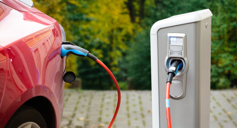 A car sits plugged into an outlet outside.