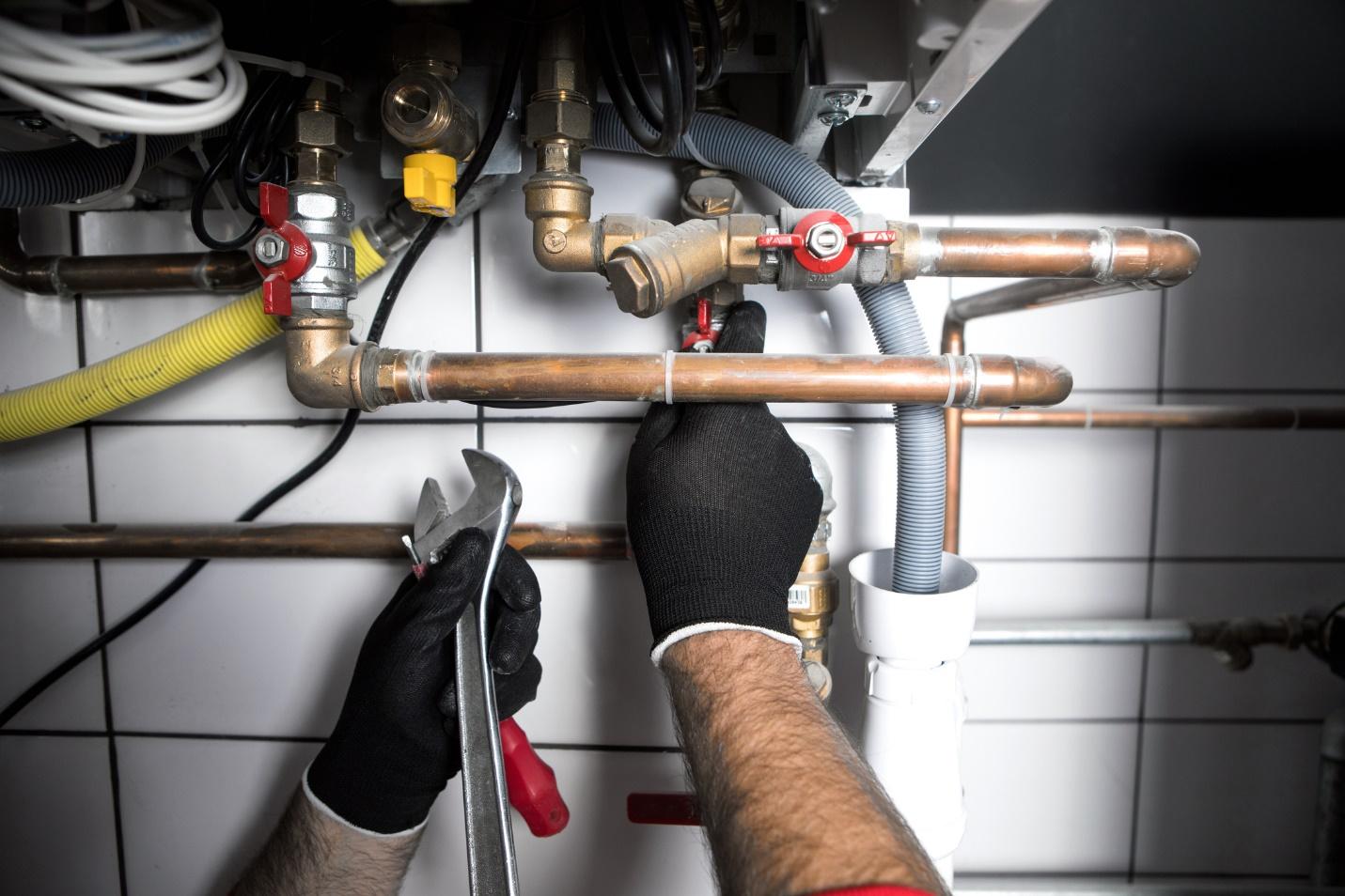 Plumber's hands replacing plumbing pipes